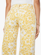Woman wearing a white top and yellow floral pants on a white background
