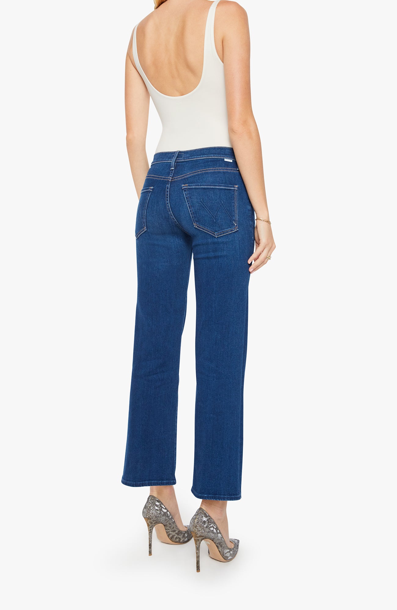 Woman wearing blue jeans and a white top on a white background