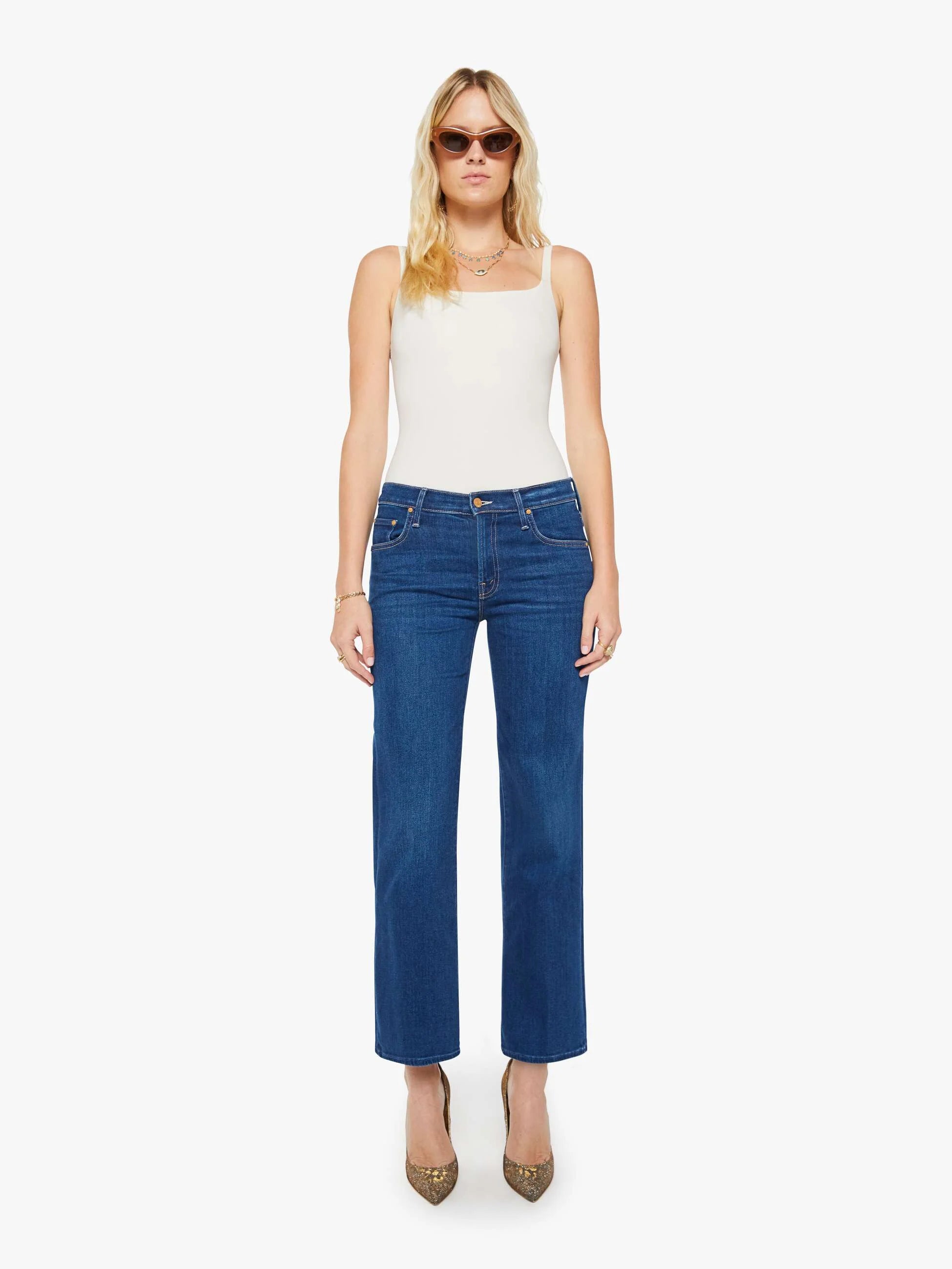 Woman wearing blue jeans and a white top on a white background
