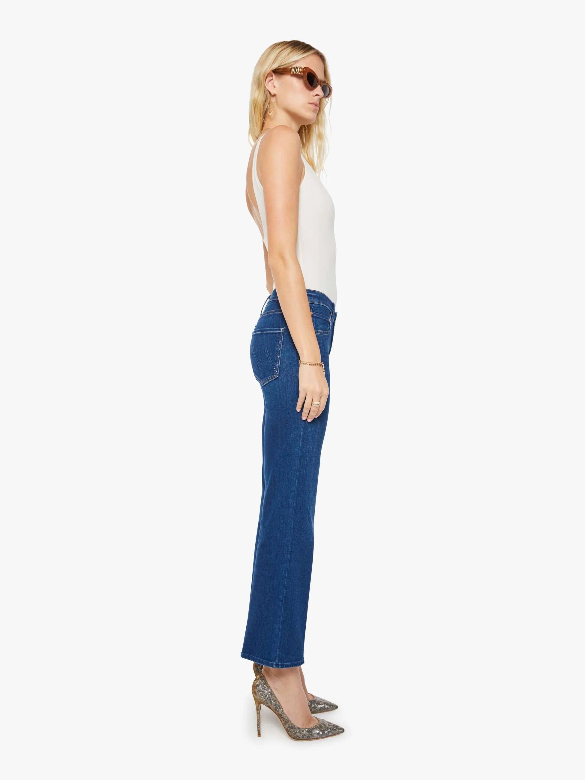 Woman wearing blue jeans and a white top on a white background
