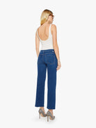 Woman wearing blue jeans and a white top on a white background