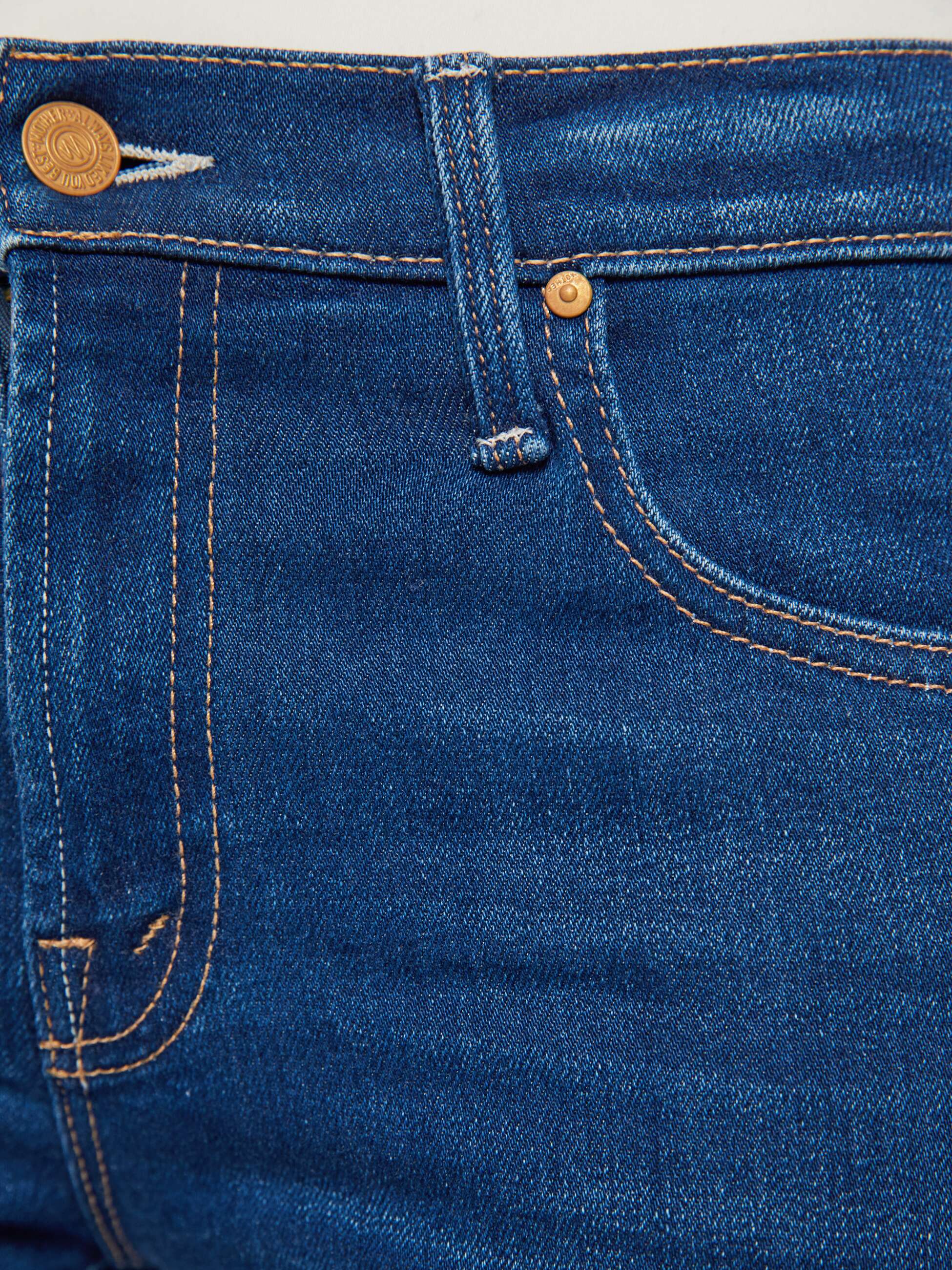 Close-up of blue denim jeans with stitching and button details.