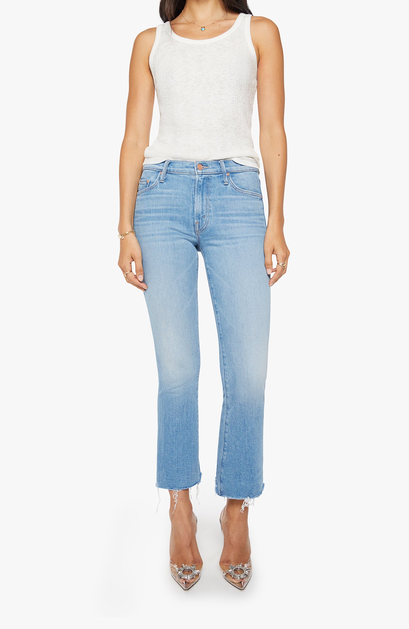 Woman wearing light blue jeans and a white top on a white background