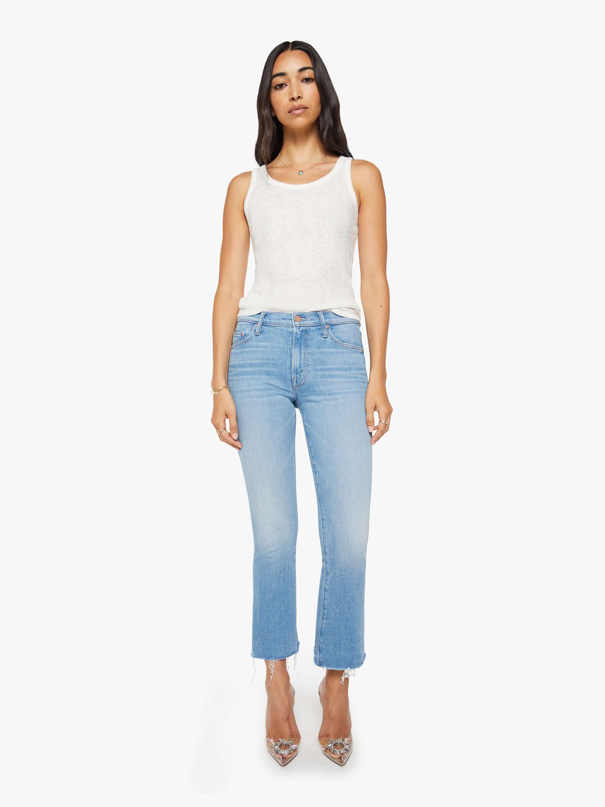 Woman wearing light blue jeans and a white top on a white background