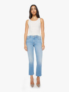 Woman wearing light blue jeans and a white top on a white background