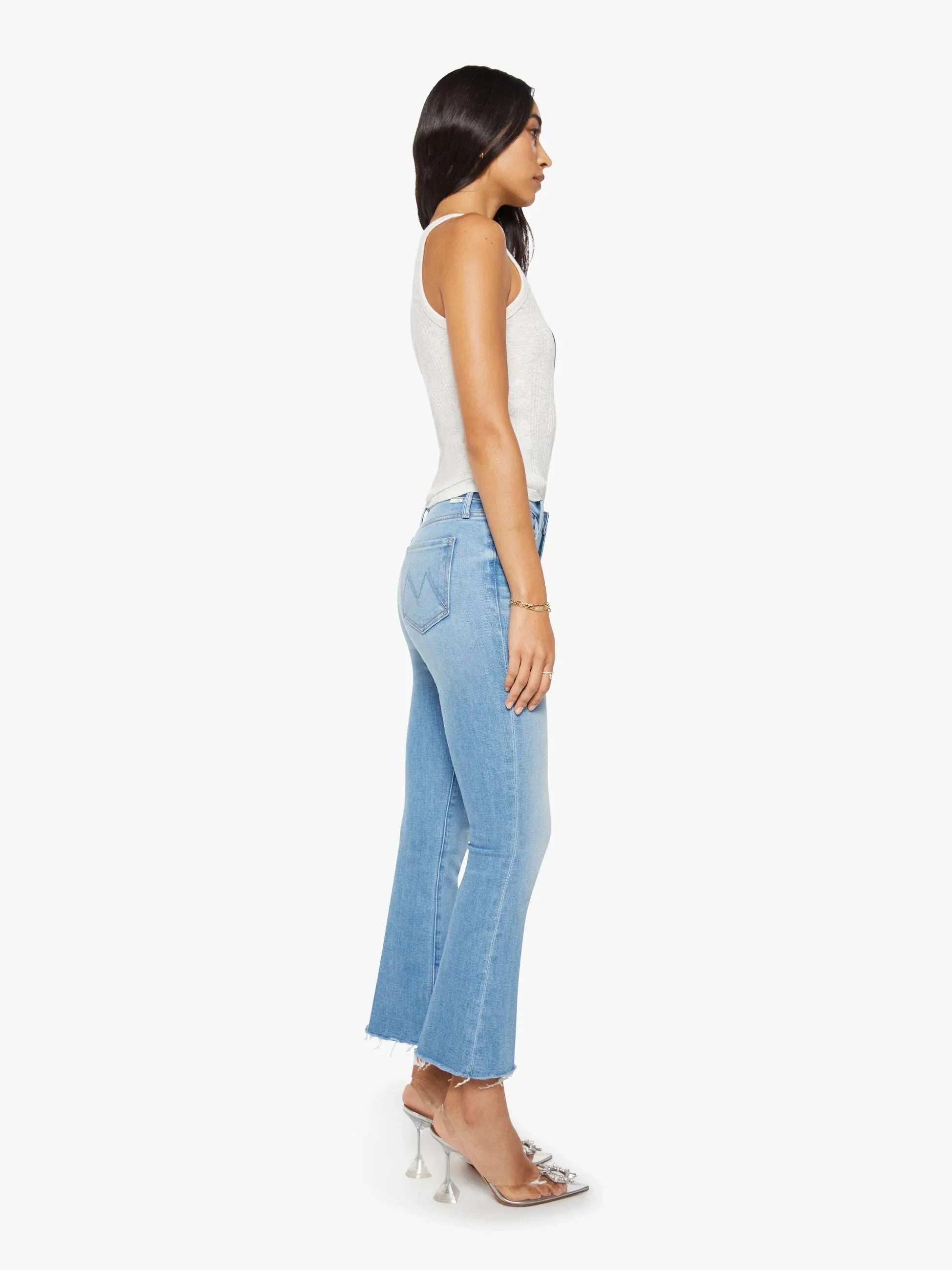 Woman wearing light blue jeans and a white top on a white background