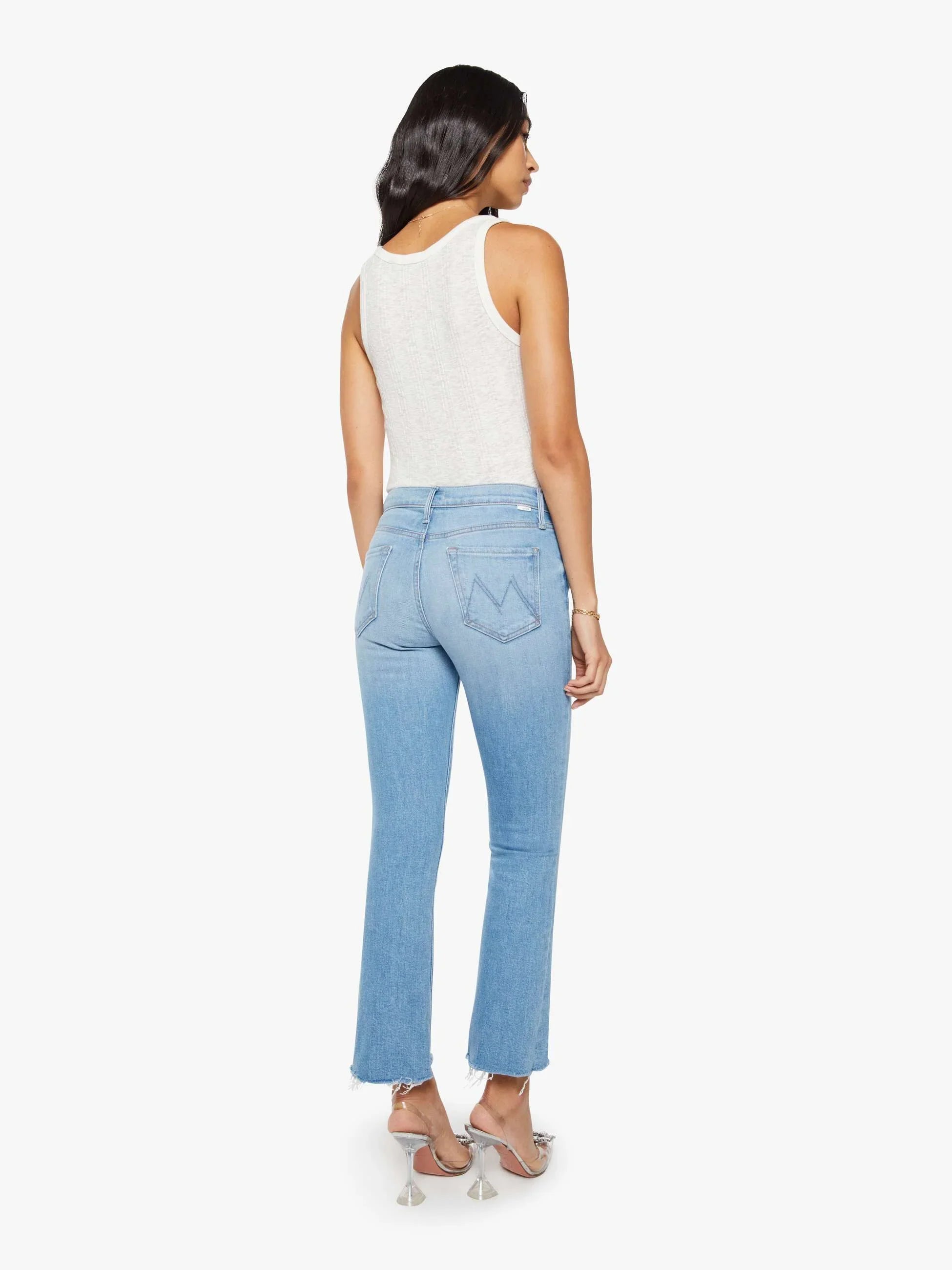 Woman wearing light blue jeans and a white top on a white background