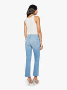 Woman wearing light blue jeans and a white top on a white background