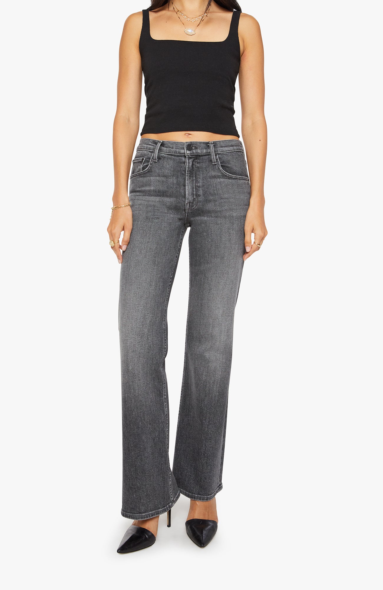 Person wearing a black tank top and gray flared jeans on a white background