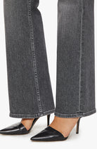 Black pointed-toe shoes worn with gray jeans on a white background