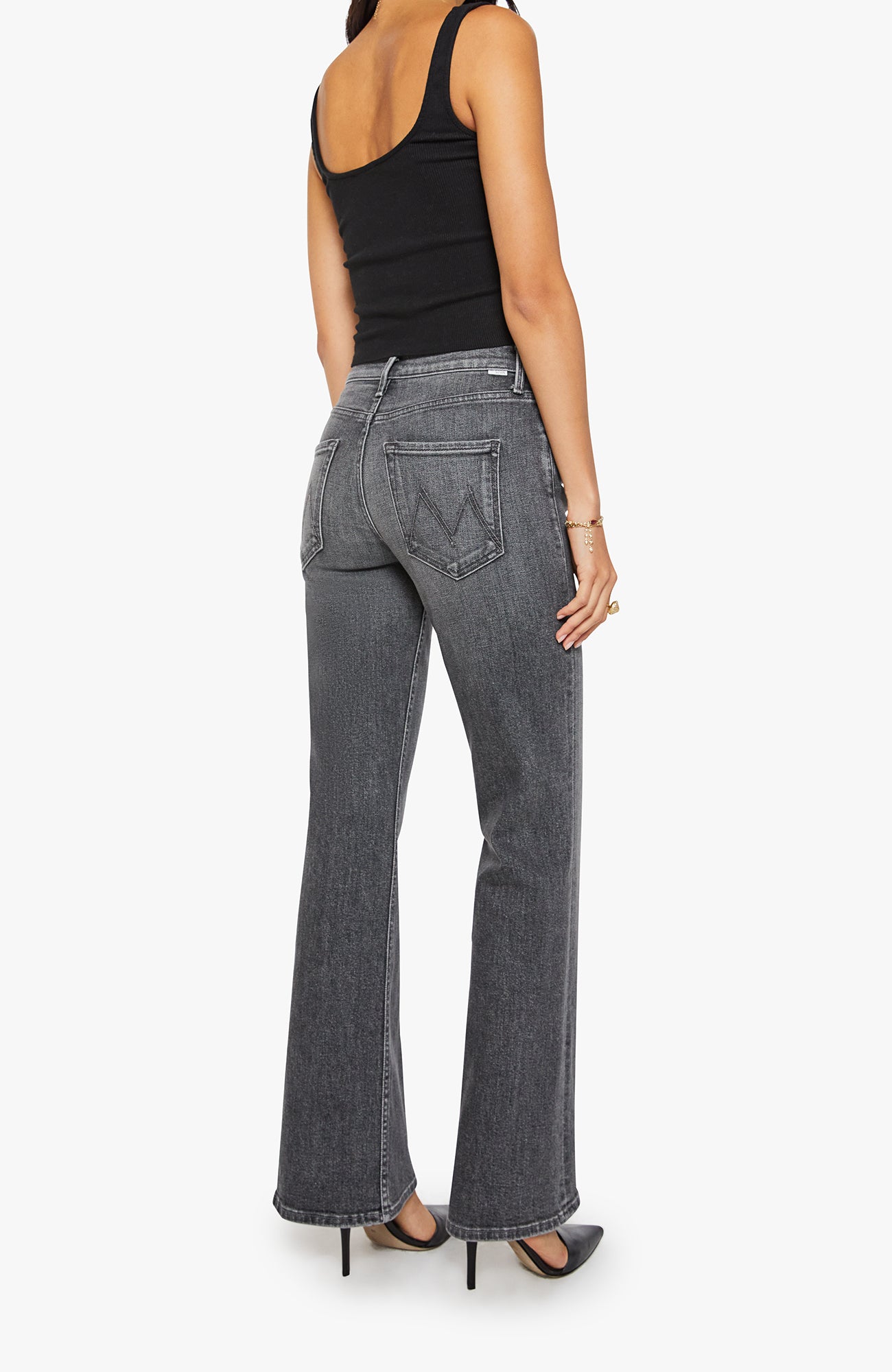 Person wearing black tank top and gray flared jeans on a white background