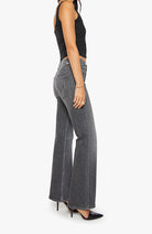 Person wearing black tank top and gray flared jeans on a white background