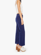 Woman wearing a white top and blue high-waisted pants on a white background