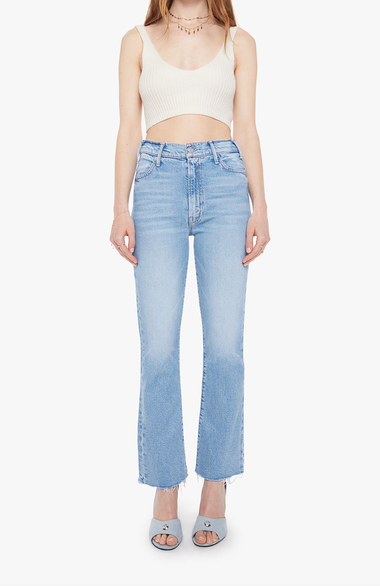 Person wearing a white crop top and light blue jeans on a white background