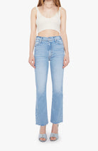 Person wearing a white crop top and light blue jeans on a white background