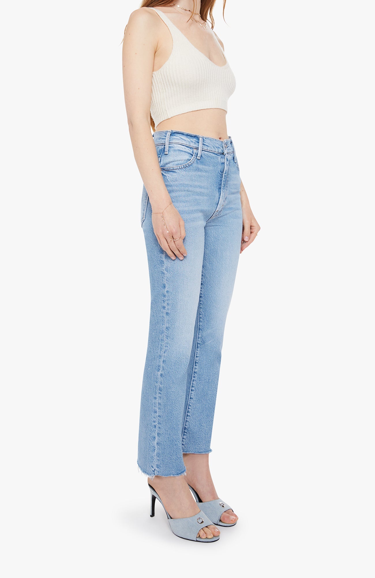 Woman wearing light blue jeans and a white crop top on a white background