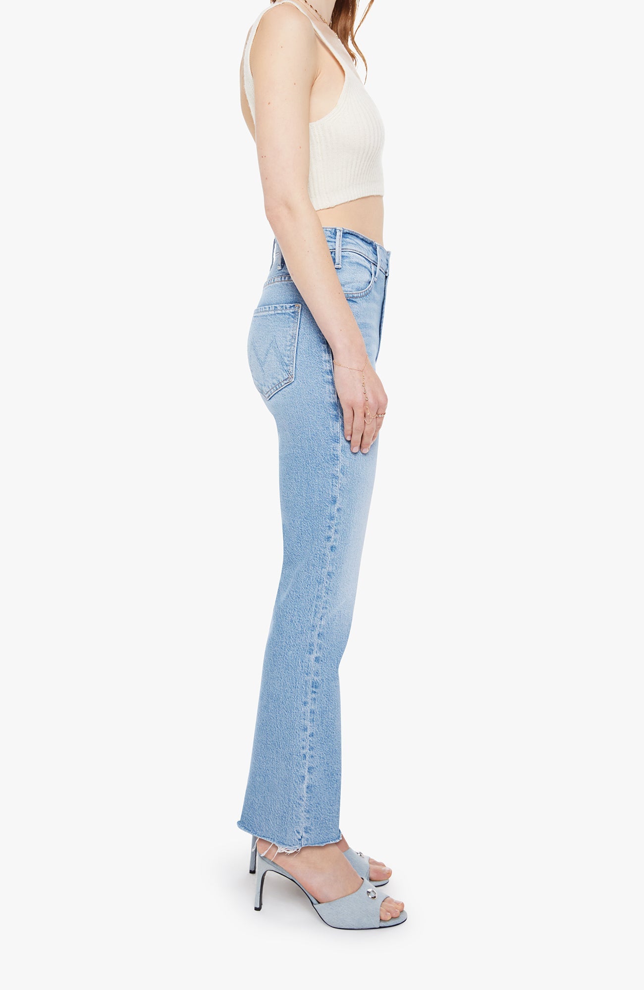 Woman wearing light blue jeans and a white top on a white background