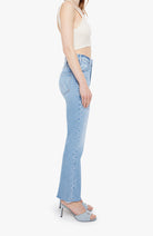 Woman wearing light blue jeans and a white top on a white background