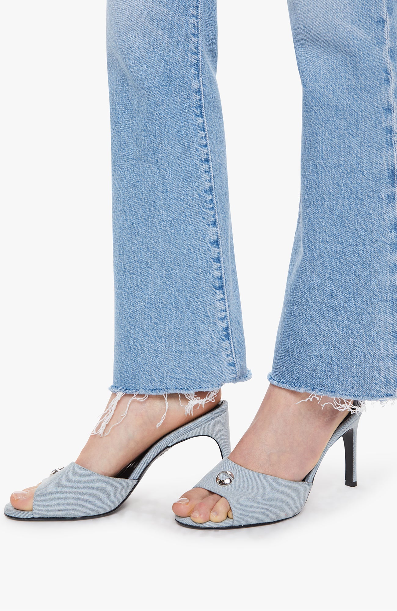 Blue high-heeled shoes worn with light blue jeans on a white background