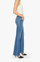 Person wearing blue flared jeans on a white background