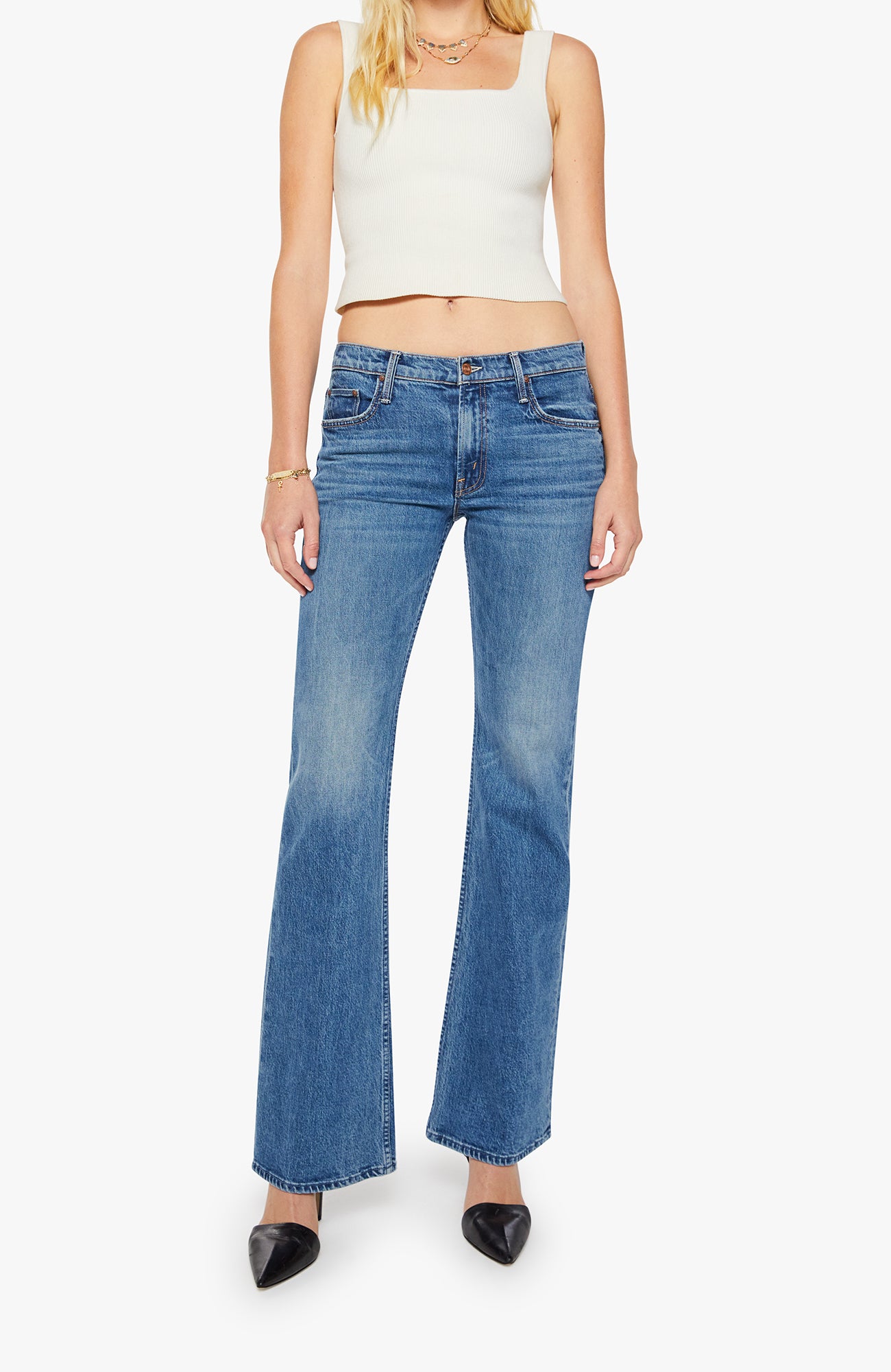 Woman wearing blue flared jeans and a white top on a white background