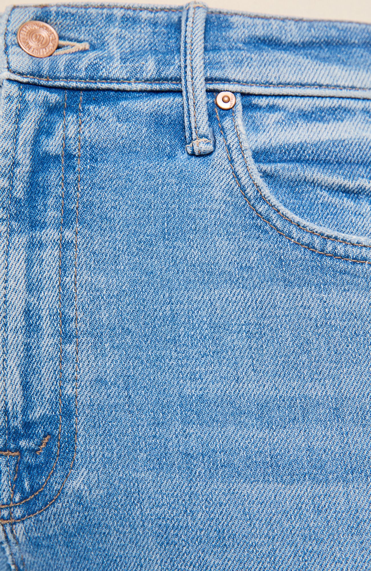 Close-up of light blue denim jeans showing the waistband, belt loops, button, front pocket, and stitching details.