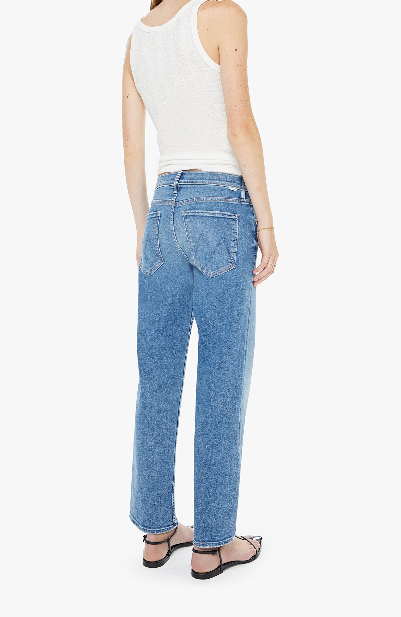 Person wearing a white tank top and blue jeans on a white background