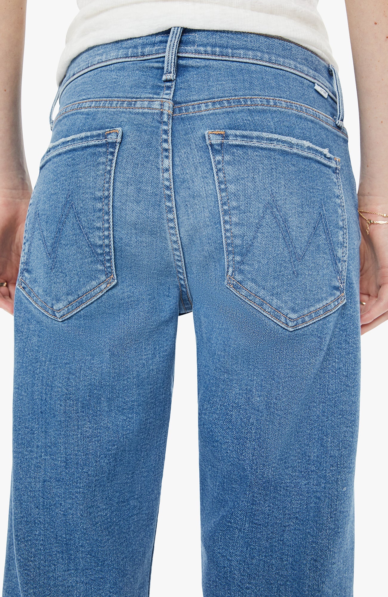 Close-up of blue jeans with a visible brand logo on a white background