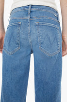 Close-up of blue jeans with a visible brand logo on a white background