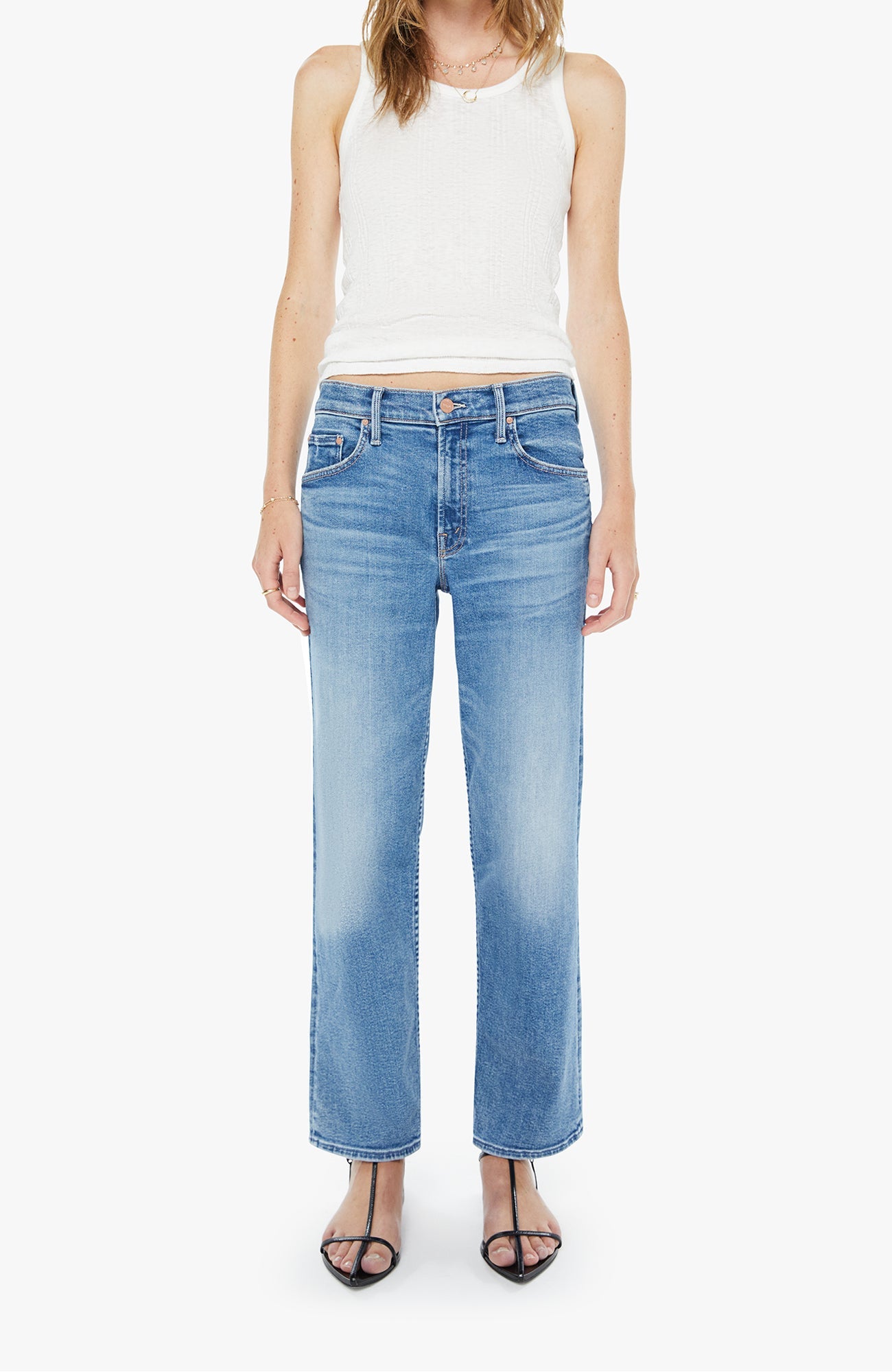 Woman wearing light blue jeans and a white sleeveless top on a white background
