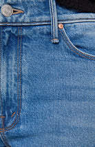 Close-up of blue denim jeans showing the front pocket, belt loop, rivet, and part of the button area.