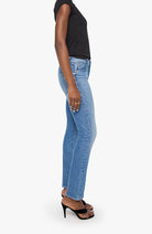 A side-profile view of a model wearing light-wash blue denim jeans, a black sleeveless top, and black high-heeled sandals against a plain light gray background.