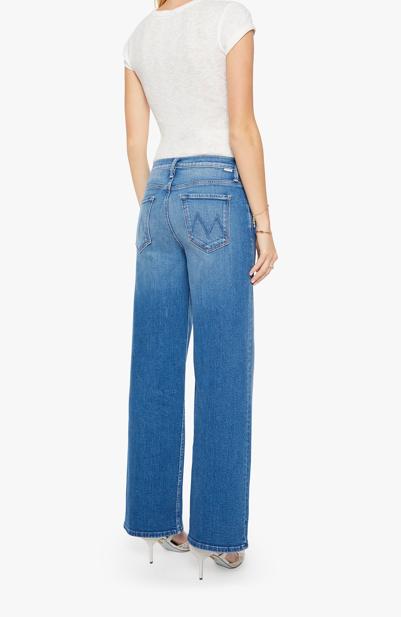 Person wearing blue jeans and a white top on a white background
