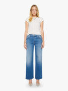 Woman wearing blue jeans and a white top on a white background