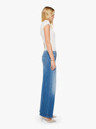 Woman wearing a white top and blue jeans on a white background