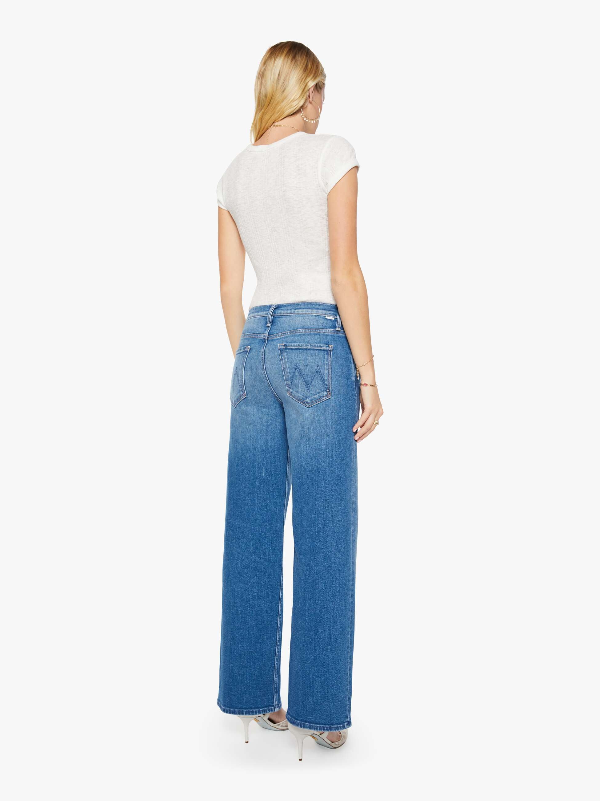 Woman wearing blue jeans and a white top on a white background