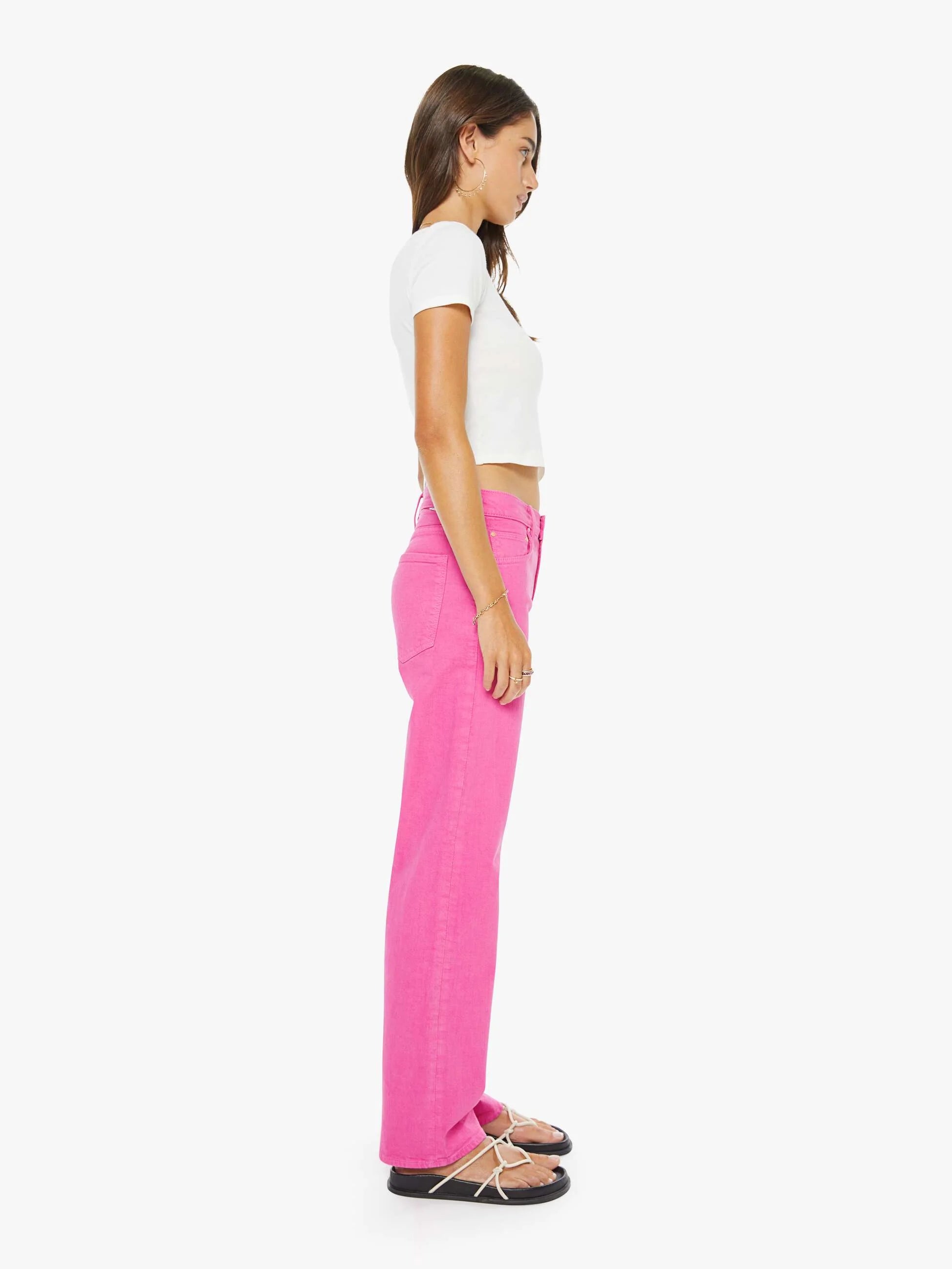 Woman wearing a white top and bright pink pants on a white background