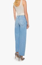 Woman wearing light blue jeans and a beige top on a white background
