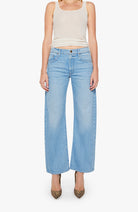 Person wearing light blue jeans and a white tank top on a white background