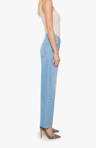 Woman wearing light blue jeans and a white top on a white background