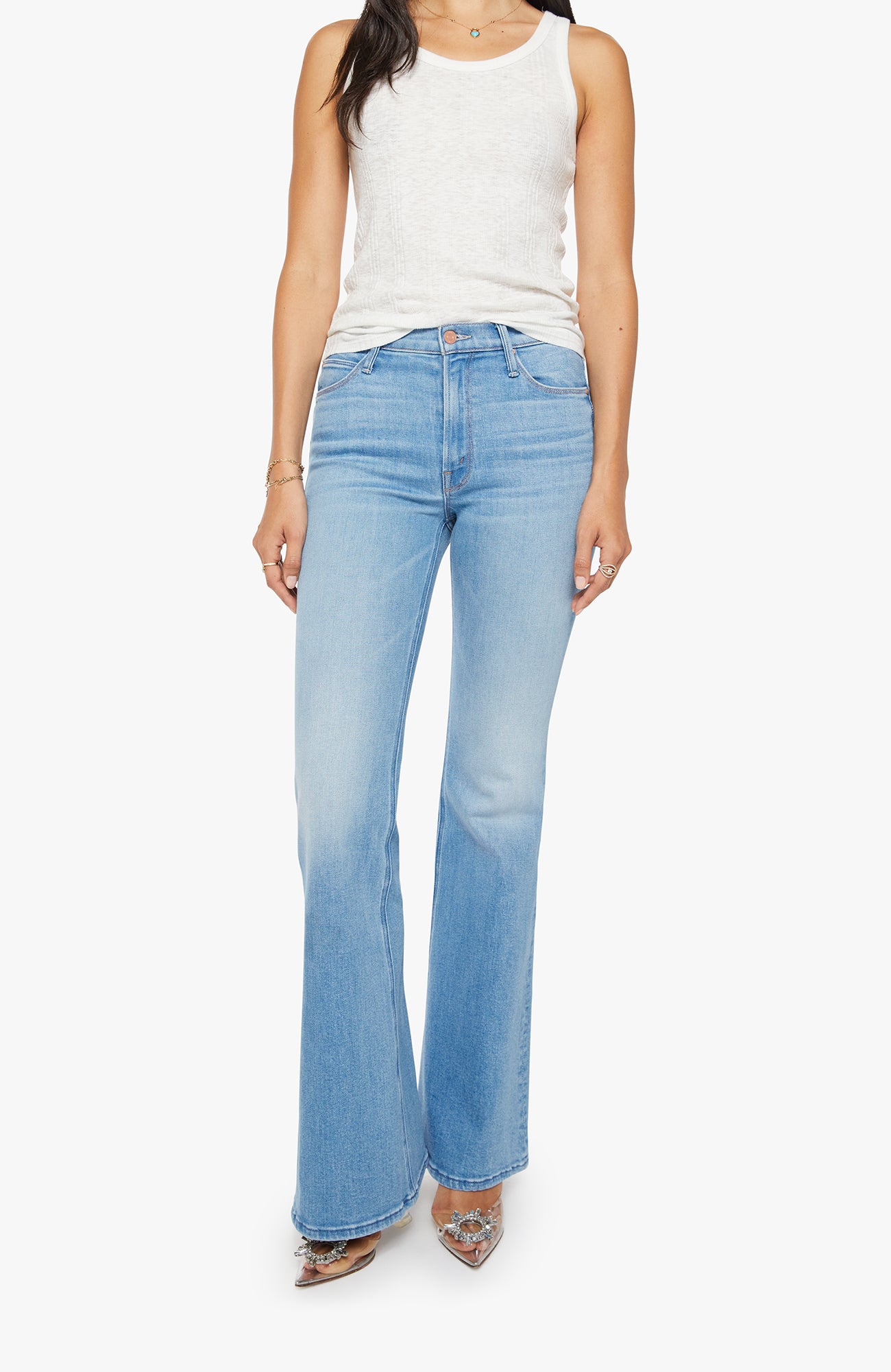 Person wearing light blue flared jeans and a white tank top on a white background