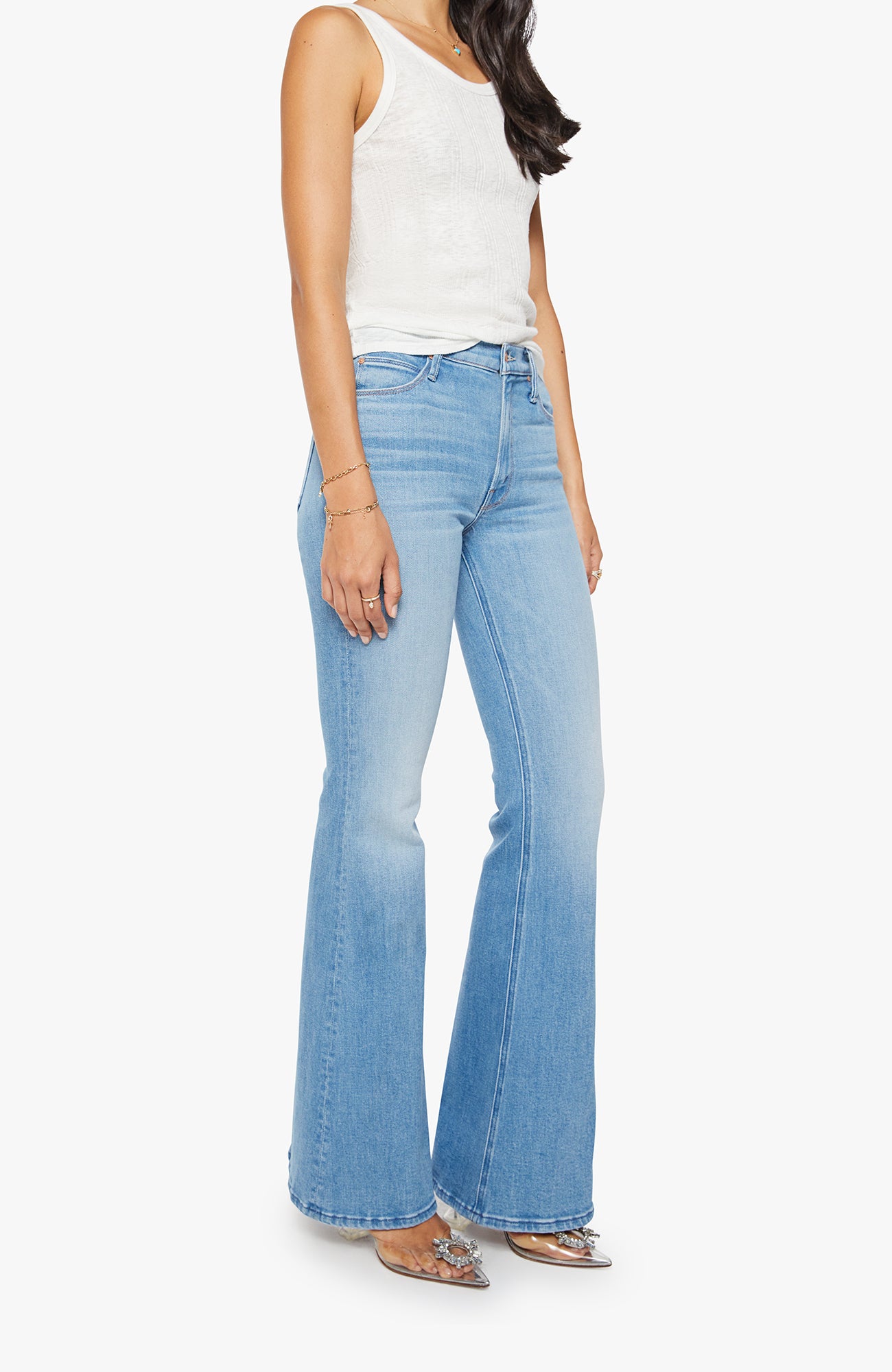 Woman wearing light blue flared jeans on a white background