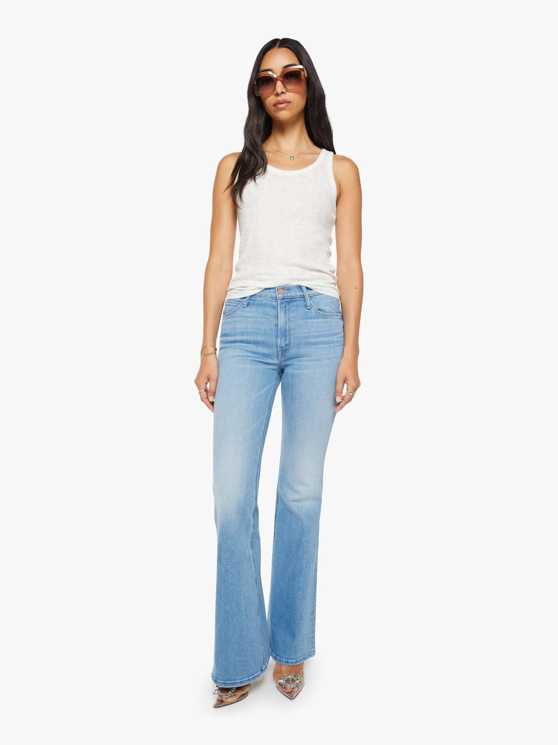 Woman wearing light blue jeans and a white top on a white background