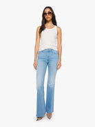 Woman wearing light blue jeans and a white top on a white background