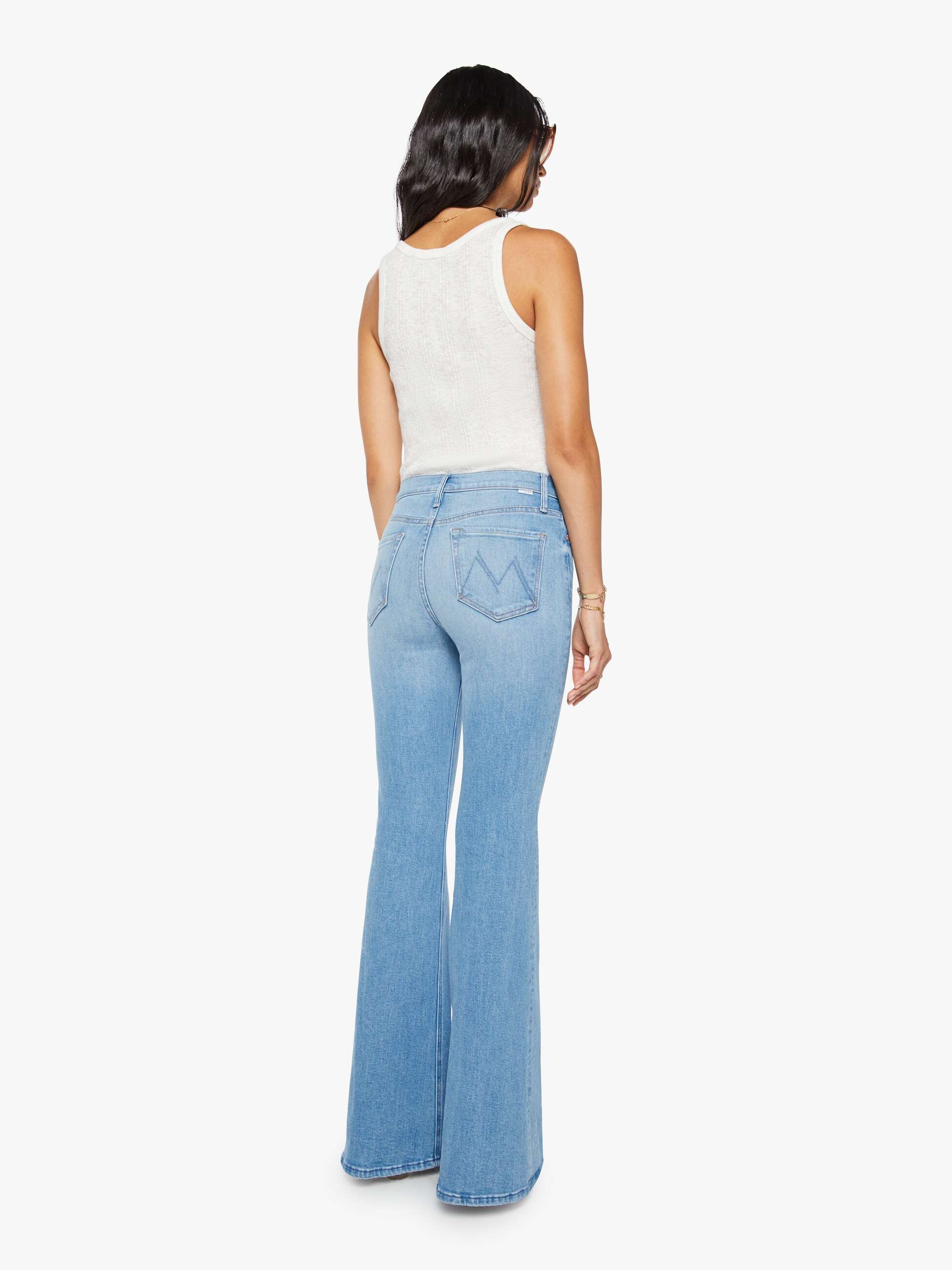 Woman wearing light blue flared jeans on a white background