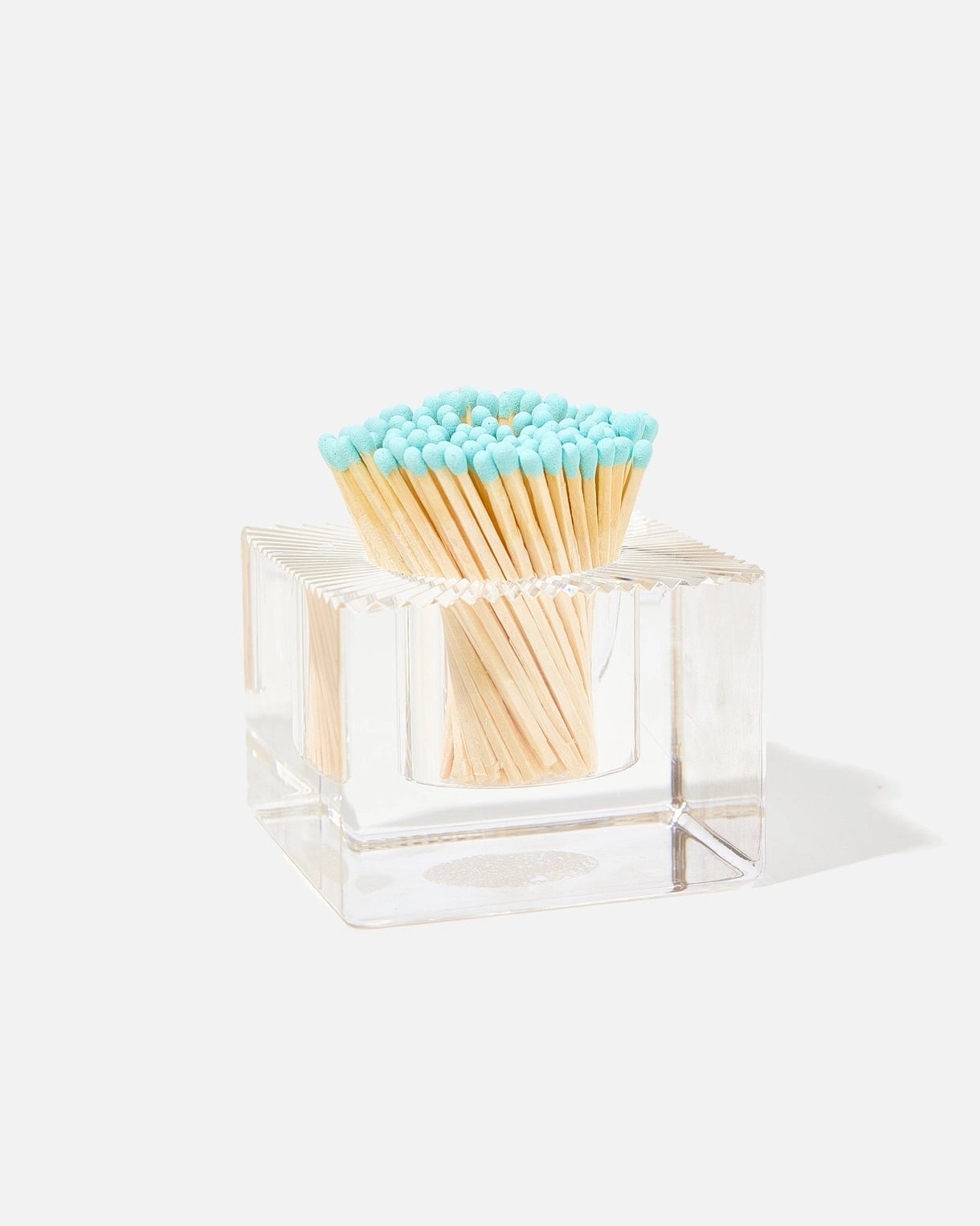 A clear acrylic square match holder filled with wooden matches that have light blue tips, photographed on a clean white background with a soft shadow.