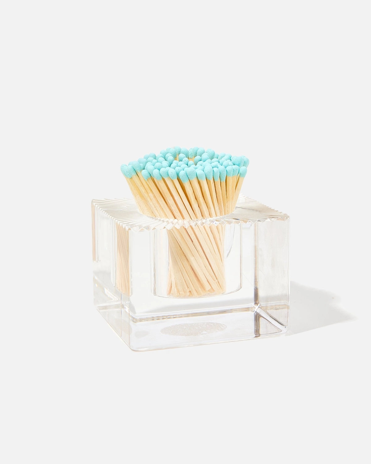 A clear acrylic square match holder filled with wooden matches that have light blue tips, photographed on a clean white background with a soft shadow.