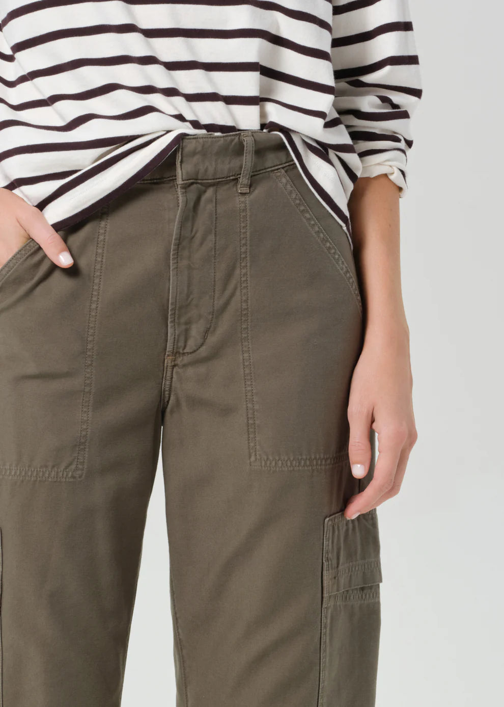 Person wearing olive green cargo pants with a striped shirt on a white background