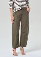 Person wearing olive green cargo pants and a striped shirt on a white background