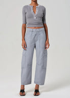 Person wearing a gray cropped top and wide-leg pants on a white background